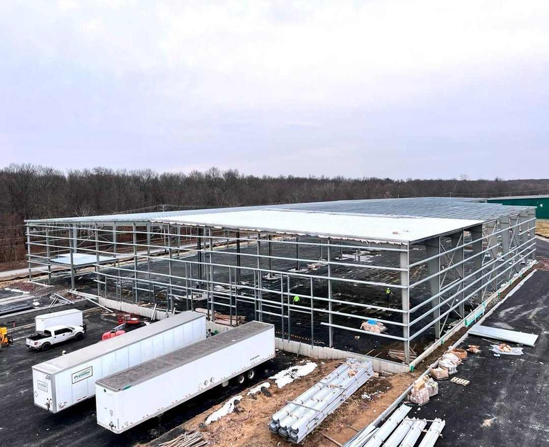 2025 Warehouse Storage Expansion Update Progress First Section Sheeted, 10 Doors Installed, Roof Bands and Cables in Place